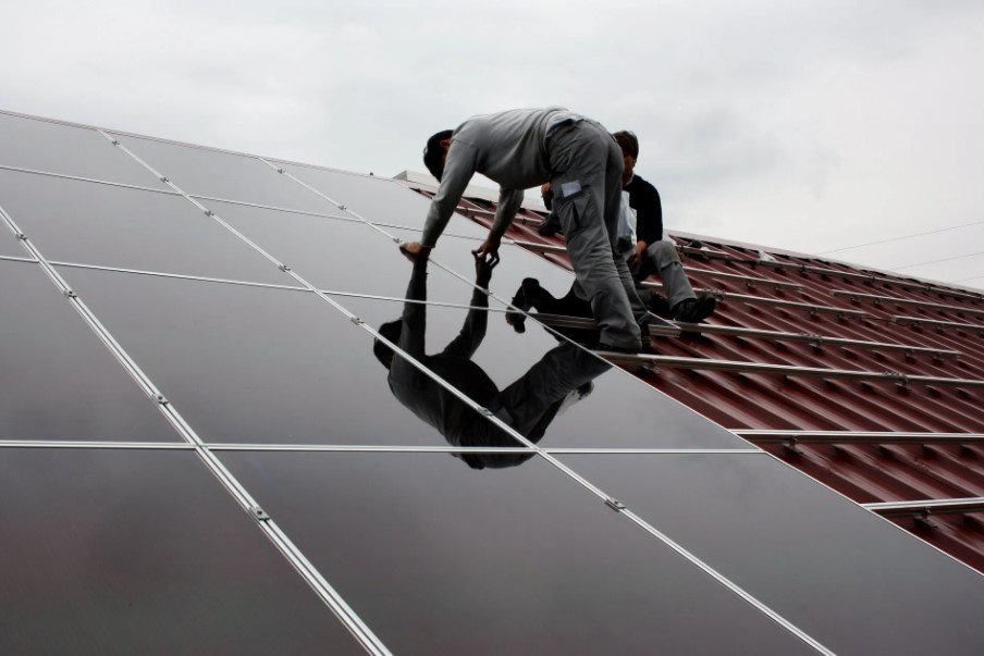 Custom made Industrial Sheds, photo of men fixing solar panels on a roof.